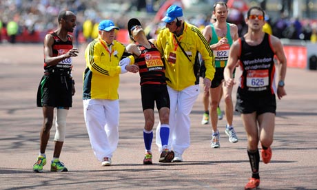 Exhausted runner helped towards the finishing line at the 2013 London Marathon
